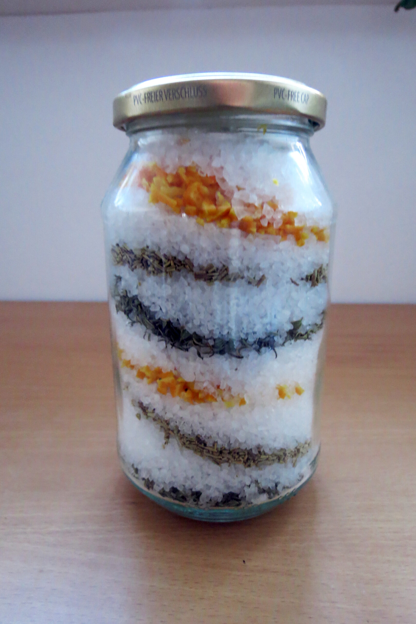 Jar with layers of salt, orange peel and herbs to make homemade orange salt