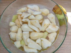 Peeled and quartered pears in a bowl with vinegar water