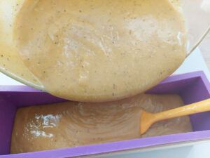 Pouring soap batter from a glass bowl into a soap mould