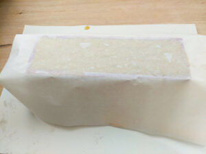 Soap mould filled with soap batter and covered with greaseproof paper