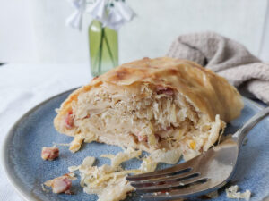 Sauerkraut strudel on a plate, one piece already missing, fork on the side