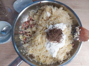 All ingredients for the filling of sauerkraut strudel in a skillet, ready to be mixed