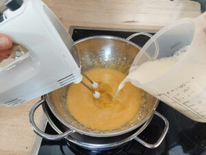 Pouring cream into an egg-sugar mix in a bain-marie