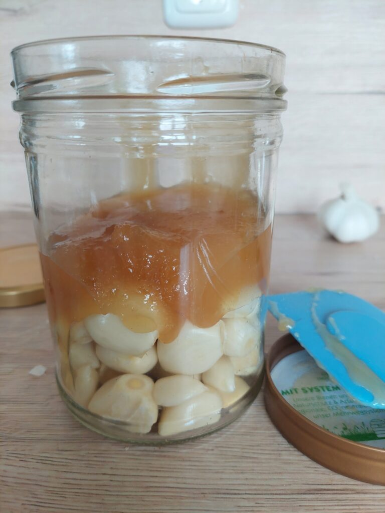 Pouring honey in a jar with garlic cloves