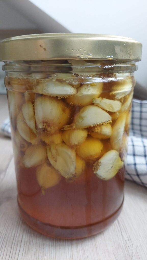 a jar of fermented garlic in honey, a chequered dishcloth in the background